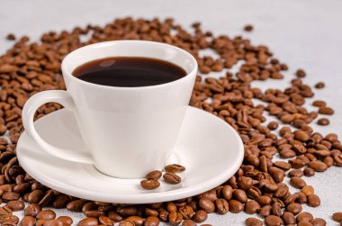 Beyaz fincanda bir fincan siyah aromatik kahve ve hafif arka planda kavrulmuş kahve çekirdekleri. Yakın plan. Yatay yönelim.