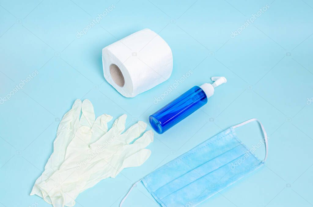 Jar with liquid soap, toilet paper, protective medical mask, white rubber gloves on a blue background. Coronovirus, Covid-19, Quarantine, Pandemic. View from above. Flat lay, copy space.