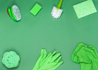 Temizlik, temizlik ve hijyen kavramı. Temizlik malzemeleri - bez, fırça, bez, sünger eldiven, yeşil arka plan. Yukarıdan bak. Düz yat, boşluğu kopyala.