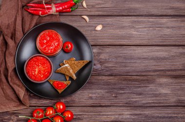 Ayvar ya da pindjur kırmızı sebze ezmesi ya da kırmızı biber biberi ve domates kremasını siyah bir tabakta, kırsal bir ahşap masada. Sırp yerlisi, geleneksel yemekler. Uzayı kopyala Yukarıdan görüntüle.