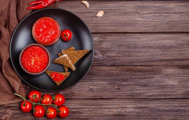 Ayvar ya da pindjur kırmızı sebze ezmesi ya da kırmızı biber biberi ve domates kremasını siyah bir tabakta, kırsal bir ahşap masada. Sırp yerlisi, geleneksel yemekler. Uzayı kopyala Yukarıdan görüntüle.