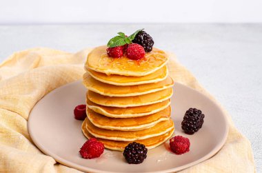 Taze ahududu, böğürtlen, bal ve nane yapraklı ev yapımı klasik Amerikan krepleri. Uzayı kopyala, düz yat. Sağlıklı yaz kahvaltısı. Yakın plan. Yukarıdan görüntüle.