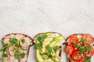 Hafif arka planda krem peynirli ve sebzeli mini sandviçler. Peynirli sandviç, turp, domates, avkado, mikroyeşil, üst manzara. Sağlıklı atıştırmalıklar. Uzayı kopyala, düz yat.