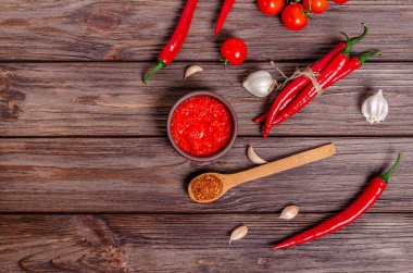 Ayvar ya da pindjur kırmızı sebze ezmesi ya da kil kasede biber biberi ve domates kreması ve kırsal ahşap bir masa üzerindeki malzemeler. Sırp yerlisi, geleneksel yemekler. Uzayı kopyala Yukarıdan görüntüle.