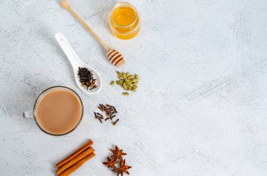Geleneksel bir Hintli, içinde yemek pişirmek için malzemeler olan cam bir fincanda masala çayı içer. Tarçın, kakule, anason, bal, karanfil, arka planda kuru çay. Yukarıdan görüntüle. Metin için boşluk kopyala, düz yat