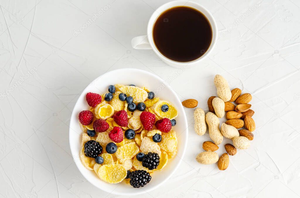 Healthy breakfast with cornflakes, raspberries, blackberries, blueberries, peanuts nuts on a white background. Copy space, flat lay, healthy snacks, quick breakfast. View from above.