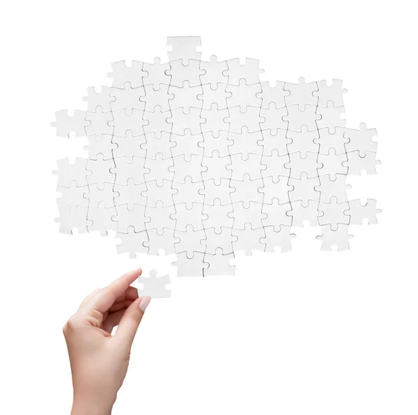 Hand holding a piece of white uncompleted puzzle — Stock Photo, Image