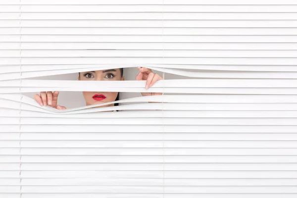 Portrait of a woman looking through out the blinds