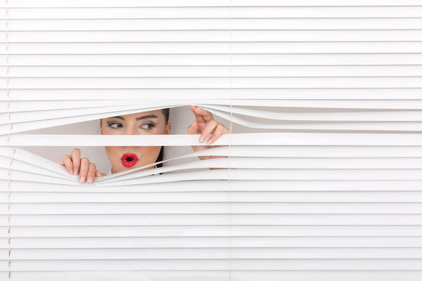 Portrait of a woman looking through out the blinds