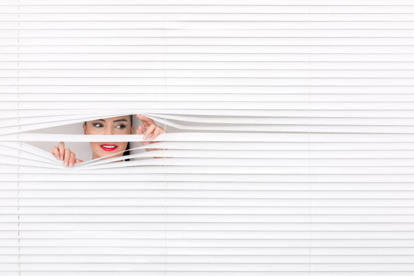 Portrait of a woman looking through out the blinds