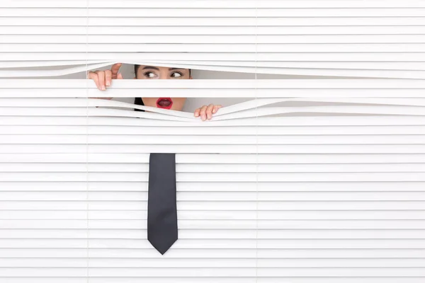 Portrait of a woman looking through out the blinds