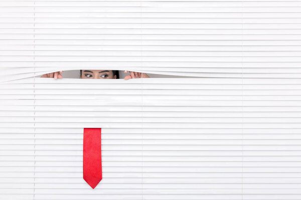 Portrait of a woman looking through out the blinds