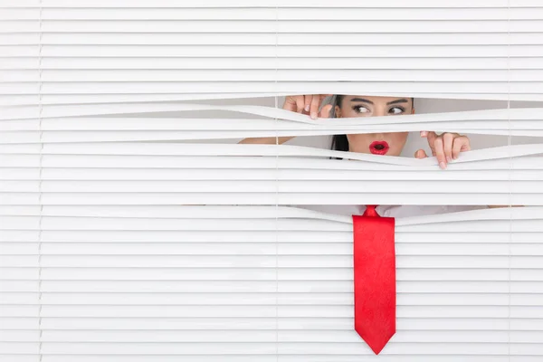 Portrait of a woman looking through out the blinds — Stock Photo, Image