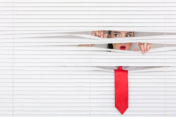Portrait of a woman looking through out the blinds
