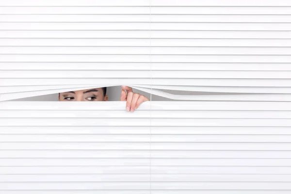 Portrait of a woman looking through out the blinds