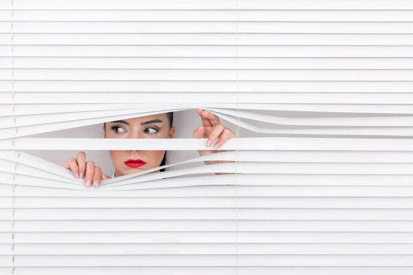 Portrait of a woman looking through out the blinds