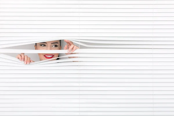 Portrait of a woman looking through out the blinds — Stock Photo, Image