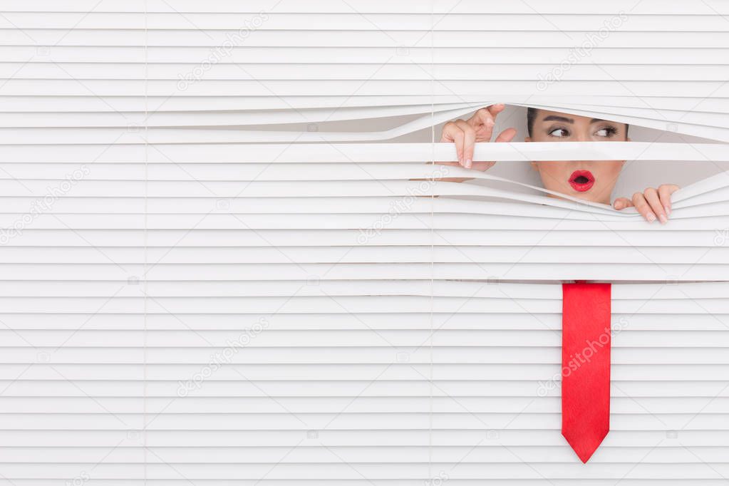 Portrait of a woman looking through out the blinds