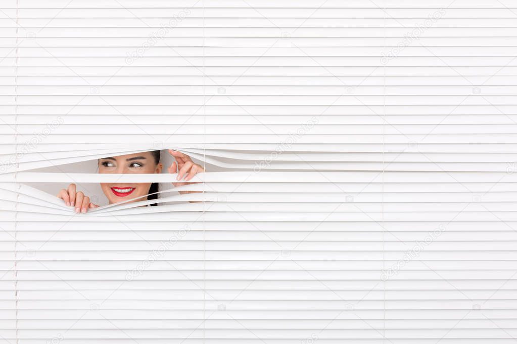 Portrait of a woman looking through out the blinds
