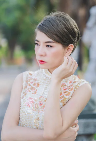 Asyalı bir kadın krem renkli bir Çin elbisesi giyiyor. Mutlu Çin Yeni Yılı.