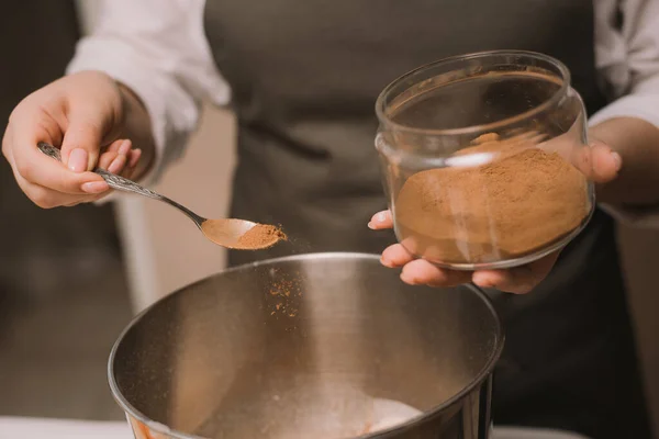 A cozinheira derrama açúcar de cana marrom em uma tigela de metal. Cozinhar doces na cozinha . — Fotografia de Stock