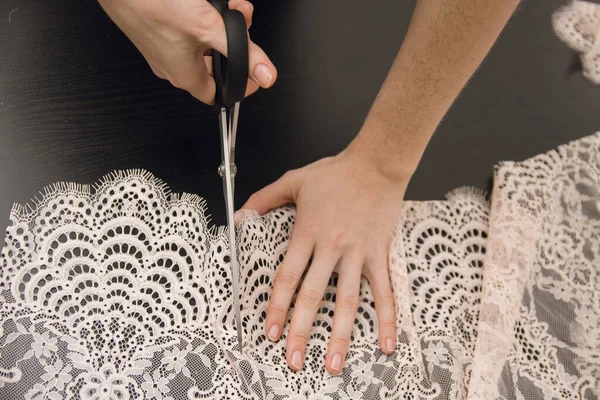 Девушка обрезает кружево. Швея режет ткань для шитья. — стоковое фото