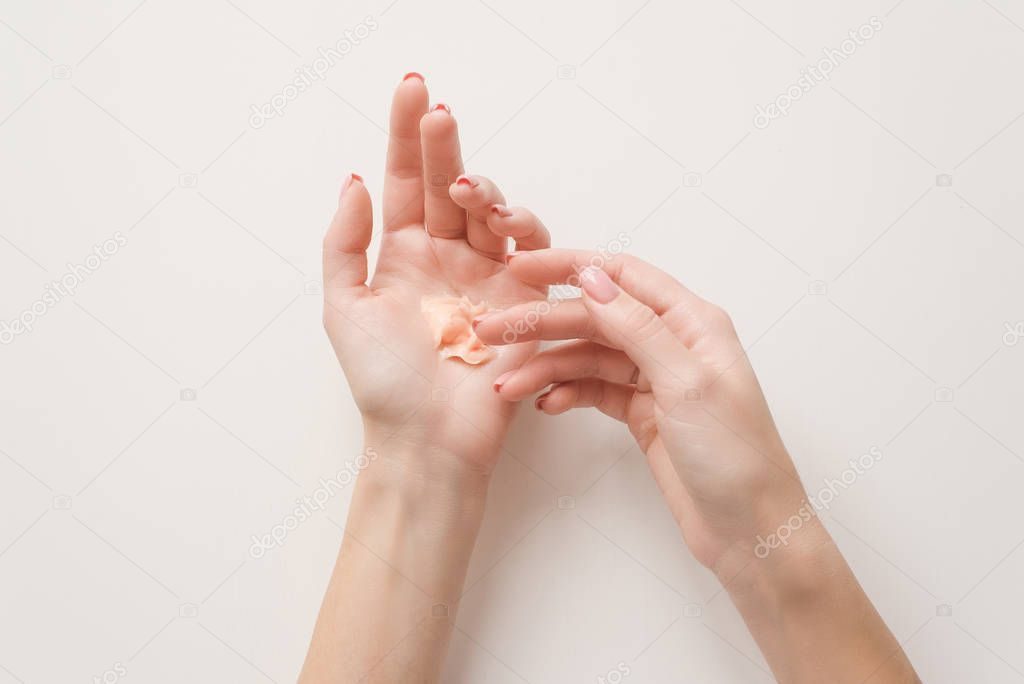 The girl distributes moisturizing cream on her hands. Hands on a white background with a jar of white cream. Flat lay top view minimalism style. Beauty concept, dermatology cosmetic