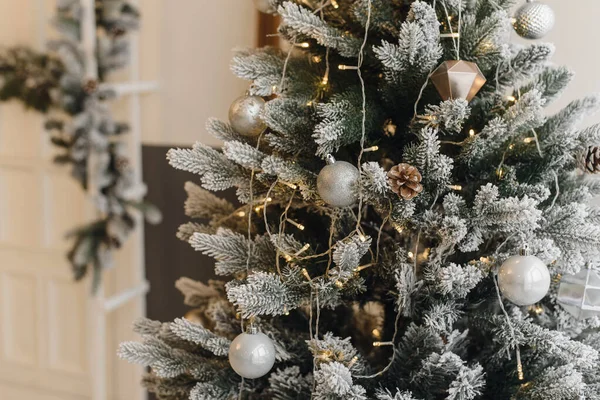 Künstlicher Weihnachtsbaum in hellem Interieur mit silbernen Blumen und Schnee auf den Zweigen. das Konzept von Neujahr und Weihnachten. — Stockfoto