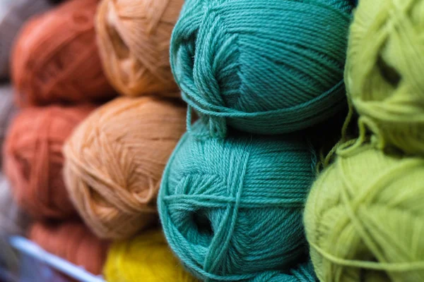 店の棚の上のウールの色の皮は針仕事のために。店頭でカラフルな糸ウールの選択。背景を編み物。ウールのニットボール、かぎ針編みのフックパターン — ストック写真