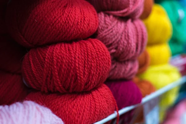 店の棚の上のウールの色の皮は針仕事のために。店頭でカラフルな糸ウールの選択。背景を編み物。ウールのニットボール、かぎ針編みのフックパターン — ストック写真