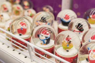 Vitrinde Noel figürleri olan karlı cam toplar. Toplu karlı gösteri..