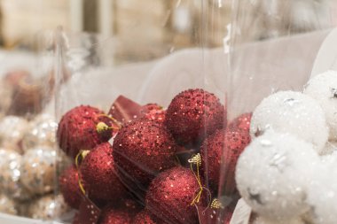 Parlak Noel topları raflardaki konteynırlarda yatıyor. Vitrinde parlayan Noel oyuncakları