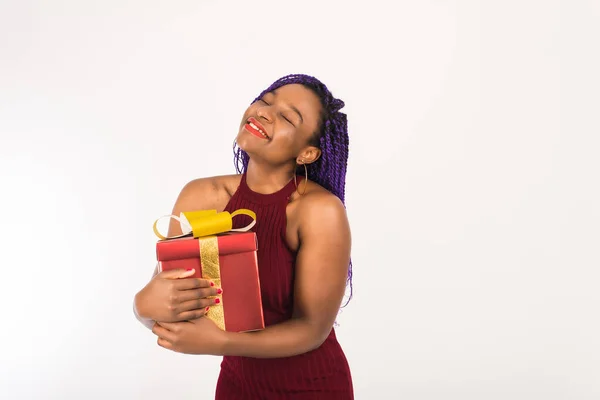 Egy sötét bőrű lány egy hatalmas piros ajándékot tart egy arany masnival a kezében, a kamerába néz és mosolyog. Fogalma ünnep, Szilveszter és Karácsony, ajándékot kap a születésnap és Valentin-nap — Stock Fotó