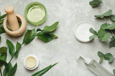 Gri arka planda kozmetik ürünleri olan düz kompozisyon. Doğal organik botanik, alternatif bitki ilaçları, doğal cilt bakım ürünleri. Doğal kozmetik ürünlerinin bir havan topu içinde yaratılması 