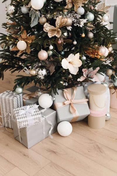 Brillantes regalos de plata en el embalaje y con lazos bajo el árbol de Navidad en el suelo. Decoraciones navideñas. Fondo de Navidad. Hermosa habitación decorada de vacaciones con árbol de Navidad con regalos un — Foto de Stock