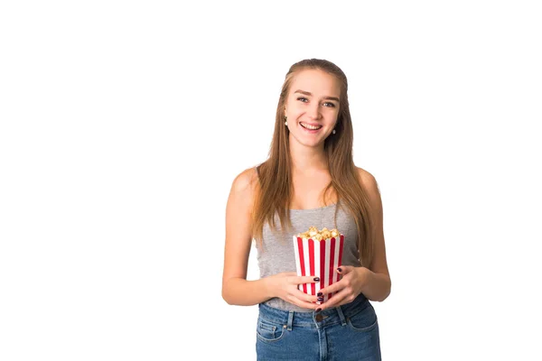 Uma garota bonita em um top de tanque cinza sorri para a câmera e segura milho pop em sua mão. Menina assistindo um filme e se divertindo, rindo. Isolado. O conceito de cinemas, filmes e exibições de filmes — Fotografia de Stock