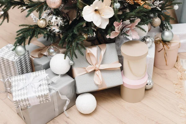 Brillantes regalos de plata en el embalaje y con lazos bajo el árbol de Navidad en el suelo. Decoraciones navideñas. Fondo de Navidad. Hermosa habitación decorada de vacaciones con árbol de Navidad con regalos un —  Fotos de Stock