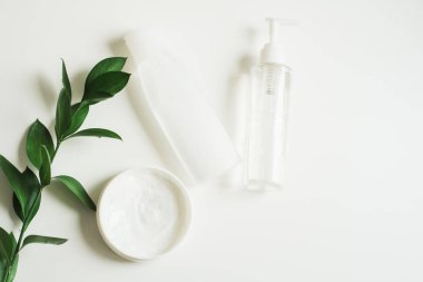 Means for skin care, rejuvenation and hydration of the face. Cream, micellar water and moisturizing lotion on a white background with a branch of green . The philosophy of self care and skin care