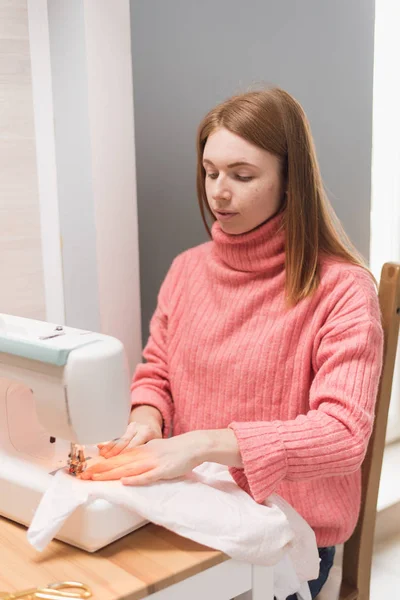 La couture fonctionne sur une machine à coudre. La fille coud et tient un tissu rose — Photo