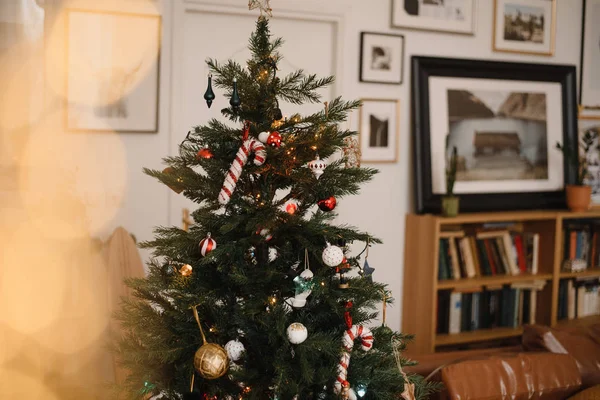Vánoční stromek s hračkami, dekoracemi a girlandami, světla v hnědém stylovém pokoji. Nový rok teplý stylový interiér — Stock fotografie