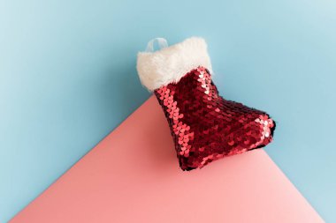 Tatil sembolü çorap. Kırmızı Noel çorabı. Pastel arka planda Noel ağacı oyuncağı. Pembe ve mavi arka planda Noel Baba çorabı