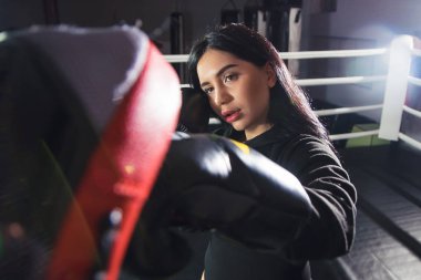 Boks eldivenli güzel bir kız ringde patilerini vuruyor. Seksi kadın spor salonunda antrenman yapıyor. Güzel esmer boks yapıyor.