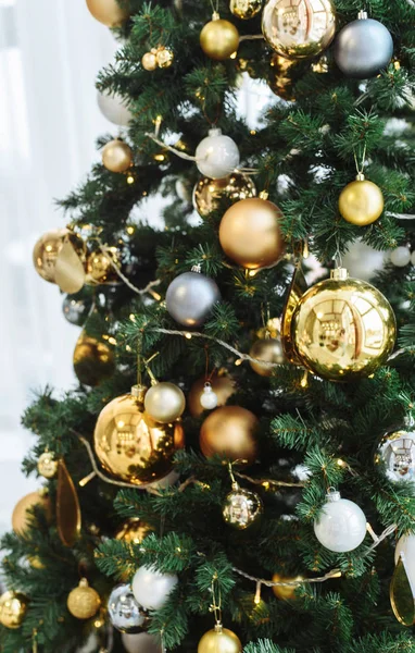 Abete di anno nuovo con decorazioni e illuminazione. Albero di Natale decorazioni sfondo. Molte grandi palle d'oro su abete Anno nuovo e Natale. Albero di Natale con palle d'oro e marroni su un verde — Foto Stock