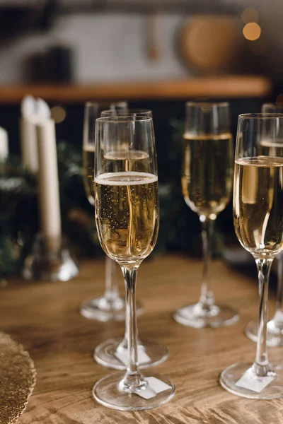 Grupo de copos de champanhe de luxo em uma mesa de madeira. Vinho branco em copos de champanhe contra o fundo de uma árvore de Natal e luzes guirlanda — Fotografia de Stock