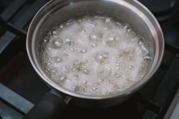 Кип'ятіть і кип'ятіть воду і цукор на сковороді на плиті. Готуємо солону карамель в домашніх умовах. Рецепт домашньої карамелі та спаленого цукру — стокове фото