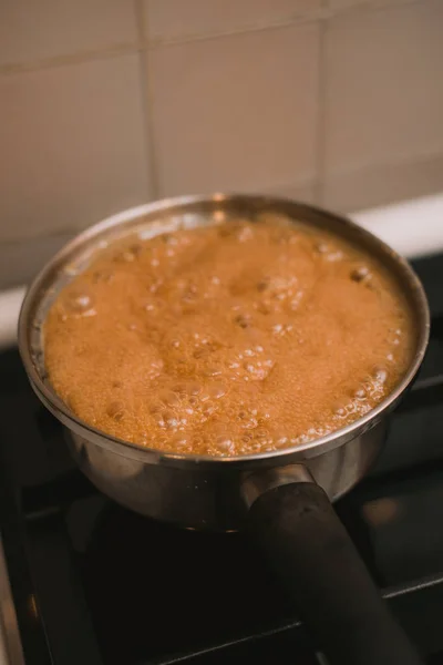 Água fervente e fervente e açúcar em uma panela no fogão. Cozinhar caramelo salgado em casa. A receita de caramelo caseiro e açúcar queimado — Fotografia de Stock
