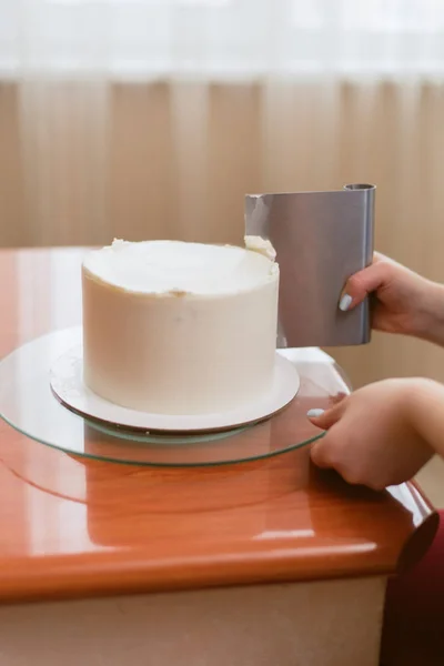 Милая девушка делает торт в пекарне. Девушка разглаживает крем на торте — стоковое фото
