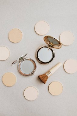 Hafif bir arka plan üzerinde kozmetik düzeni. Farklı cilt tonlarında toz refils ve makyaj fırçası yanında preslenmiş ton temeli