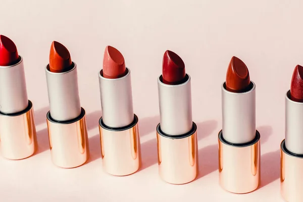 Multi-colored lipsticks stand in a row on a pink background. The concept of different, collections and beauty. Red, pink and burgundy lipsticks — Stock Photo, Image