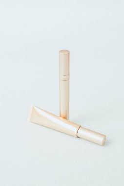 Pastel mavi arka planda farklı bir altın rimel, desen. C